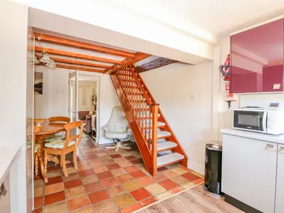 a kitchen and dining room with a spiral staircase in a house at Cameron's Cottage in Swaffham
