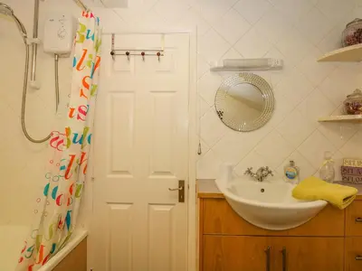 a bathroom with a sink and a shower curtain at Cameron's Cottage in Swaffham