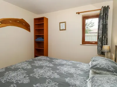 a bedroom with a bed and a window at Dragonfly Lodge in Yaxham