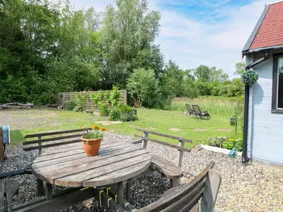 a wooden picnic table with a potted plant on it at Dragonfly Lodge in Yaxham