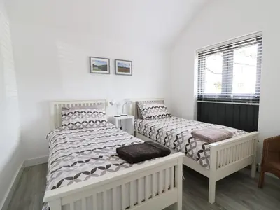two beds in a bedroom with white walls at Whitehands Farm Barn in Old Buckenham
