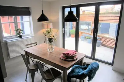 a dining room table with chairs and a vase of flowers at Crown Cottage, Orford - Prime Orford Location in Orford