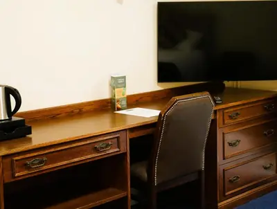 a desk with a television and a chair in a room at The New Chichester Hotel in Wickford