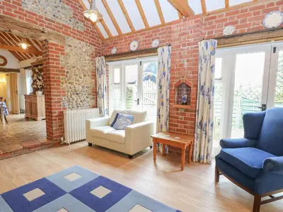 a living room with a couch and chairs in a brick wall at Stable Cottage in West Bradenham