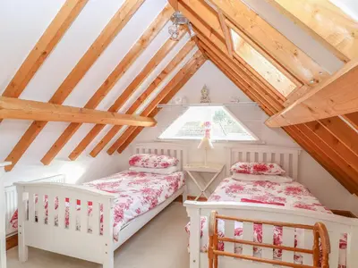 two beds in a attic room with wooden beams at Stable Cottage in West Bradenham
