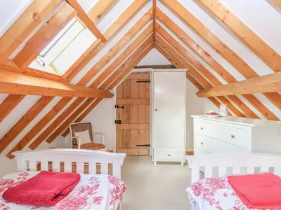 a bedroom with two white beds in a attic at Stable Cottage in West Bradenham
