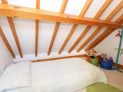 a bedroom with a white bed in a attic at Stable Cottage in West Bradenham