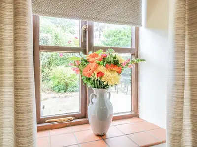 a vase filled with flowers sitting on a window sill at The Hayloft in Ashill