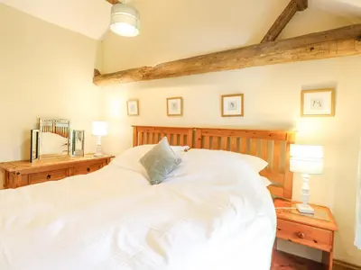 a bedroom with a large white bed with two lamps at The Hayloft in Ashill