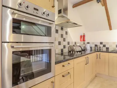 a kitchen with a stainless steel oven and counters at Hayloft Cottage in Little Glenham