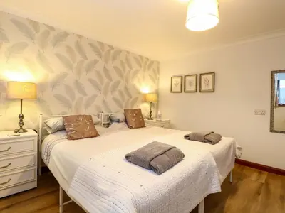 two beds in a bedroom with two lamps on it at Kingfisher in Wattisfield