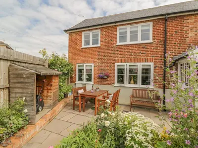 a brick house with a patio with a table and chairs at Mulberry Cottage in Hadleigh