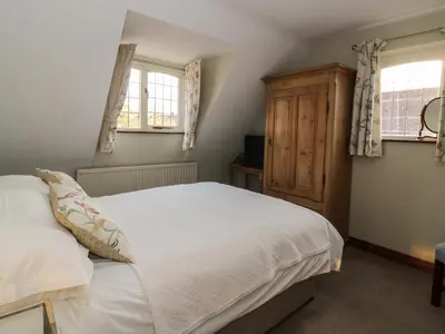 a bedroom with a white bed and two windows at The Lodge off High Street in Hadleigh