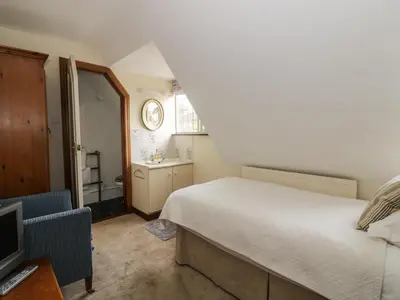 a small bedroom with a bed and a bathroom at The Lodge off High Street in Hadleigh