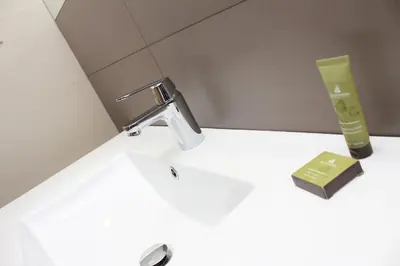 a bathroom sink with a faucet and a bottle of soap at Brentwood Hotel & Apartments in Brentwood