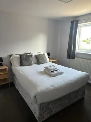 a bedroom with a bed with white sheets and a window at Coach house hotel in Royston