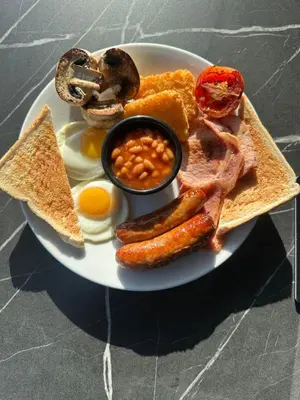 a plate of breakfast food with eggs sausage beans and toast at Coach house hotel in Royston