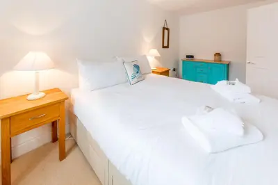 a bedroom with two beds and a night stand with a lamp at The Lobster Pot in Aldeburgh