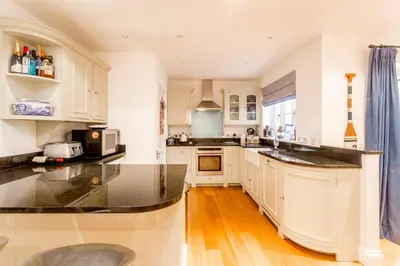 a kitchen with white cabinets and black counter tops at The Lobster Pot in Aldeburgh