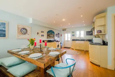 a dining room with a table and a kitchen at Shell Cottage in Aldeburgh