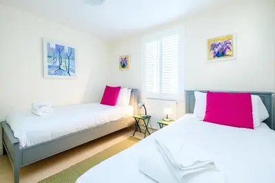 two beds in a room with pink and white at Shell Cottage in Aldeburgh