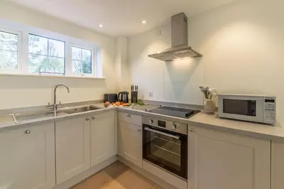 a white kitchen with a sink and a microwave at Marsh View in Aldeburgh