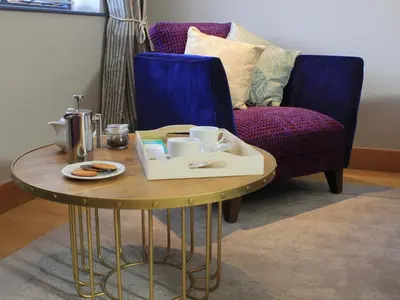 a table with a tray of food on it next to a couch at The Lodge at Hemingford Grey House in Hemingford Grey