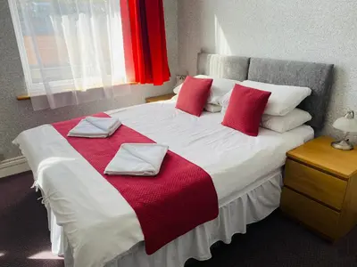 a bedroom with a large bed with red and white pillows at The Grosvenor in Clacton-on-Sea