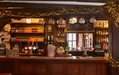 a bar with christmas lights on the wall at Bull Hotel by Greene King Inns in Long Melford