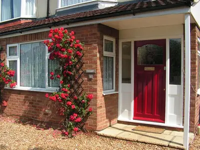 a brick house with a red door and a bush of roses at Rosa's Bed and Breakfast in Cambridge