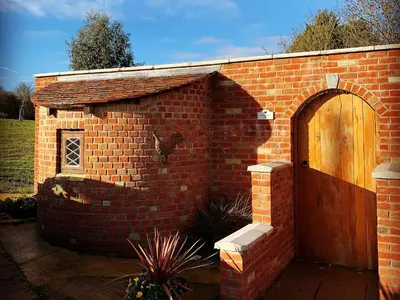 a brick building with a wooden door in a yard at Chick Hatch Barn in Kelsale