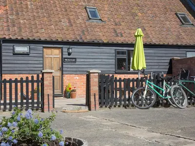 two bikes parked next to a building with an umbrella at Old Dairy - Ukc3169 in Walpole