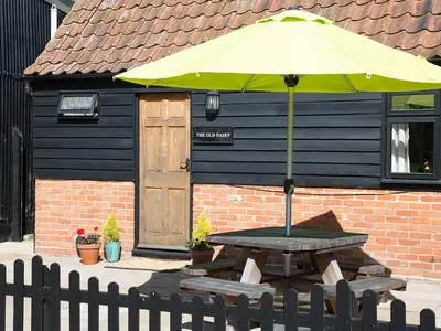 a yellow umbrella on a picnic table in front of a building at Old Dairy - Ukc3169 in Walpole