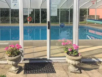 a swimming pool and two pots with pink flowers in them at Old Corn Mill - Ukc3170 in Walpole