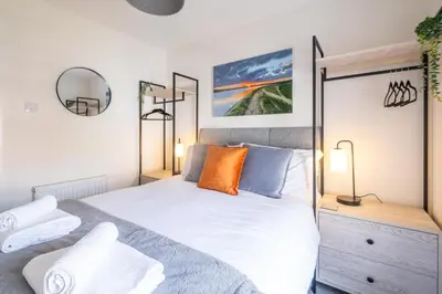 a bedroom with a large white bed and two lamps at Avocet Cottage in Aldeburgh