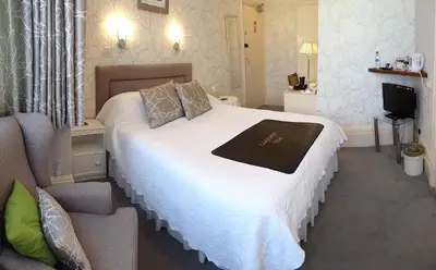 a bedroom with a white bed and a television at The Chudleigh in Clacton-on-Sea