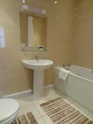a bathroom with a sink and a toilet and a tub at The Chudleigh in Clacton-on-Sea