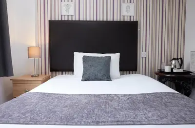 a bedroom with a large bed with a black headboard at Old Ferry Boat by Greene King Inns in St Ives