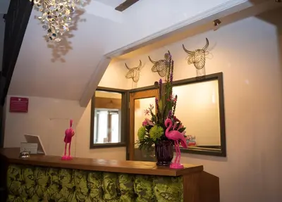 a counter with a mirror and a vase with flowers at The Bull Inn in Mildenhall