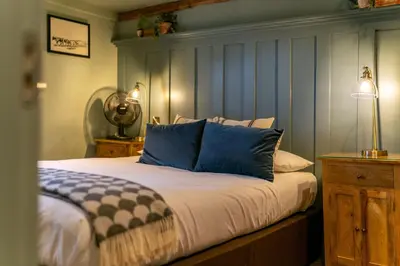 a bed with blue and white pillows in a room at The Bull Inn in Mildenhall