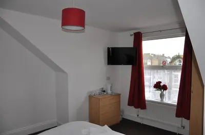 a bedroom with a bed and a window with a television at Victoria Villa Guesthouse in Clacton-on-Sea