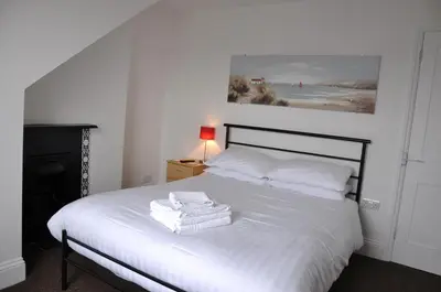 a bedroom with a white bed with towels on it at Victoria Villa Guesthouse in Clacton-on-Sea