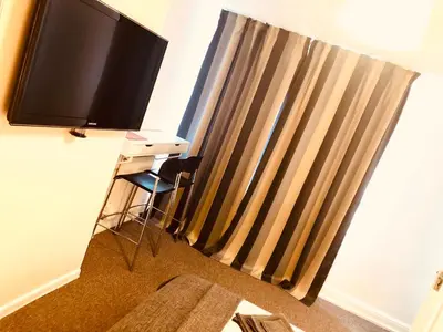 a room with a flat screen tv and a stool at AC Lounge 125 in Rochford