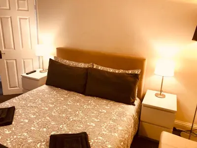 a bedroom with a bed with two night stands and two lamps at AC Lounge 125 in Rochford
