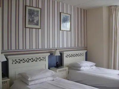 two beds in a hotel room with striped walls at The Langtry Hotel in Clacton-on-Sea