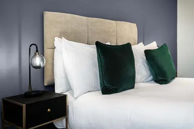 a bed with white pillows and green pillows at The Regent Aparthotel in Cambridge