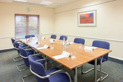 a conference room with a large wooden table and chairs at Holiday Inn Colchester by IHG in Colchester
