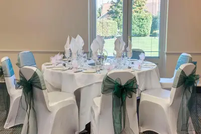 a dining room with white tables and chairs with bows at Holiday Inn Colchester by IHG in Colchester