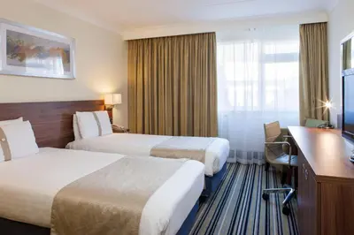 a hotel room with two beds and a desk at Holiday Inn Colchester by IHG in Colchester