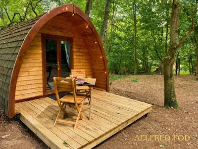 a small wooden cabin with a table and a chair on a deck at West Stow Pods in Bury St Edmunds in West Stow